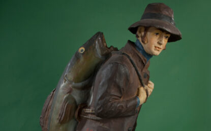 Figurine of a man in rain gear carrying large fish on his back