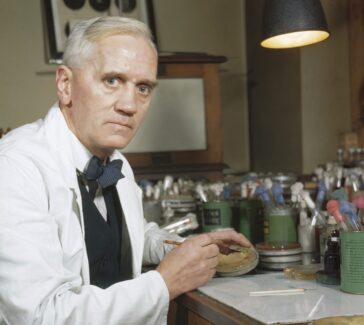 Alexander Fleming working in a lab holding a petri dish