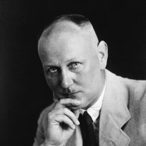 Gerhard Domagk stares towards the camera with his chin resting on his hand. he wears a light colored jacket with a dark tie.