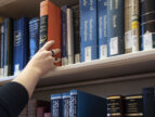 hand reaching for a book on a library shelf