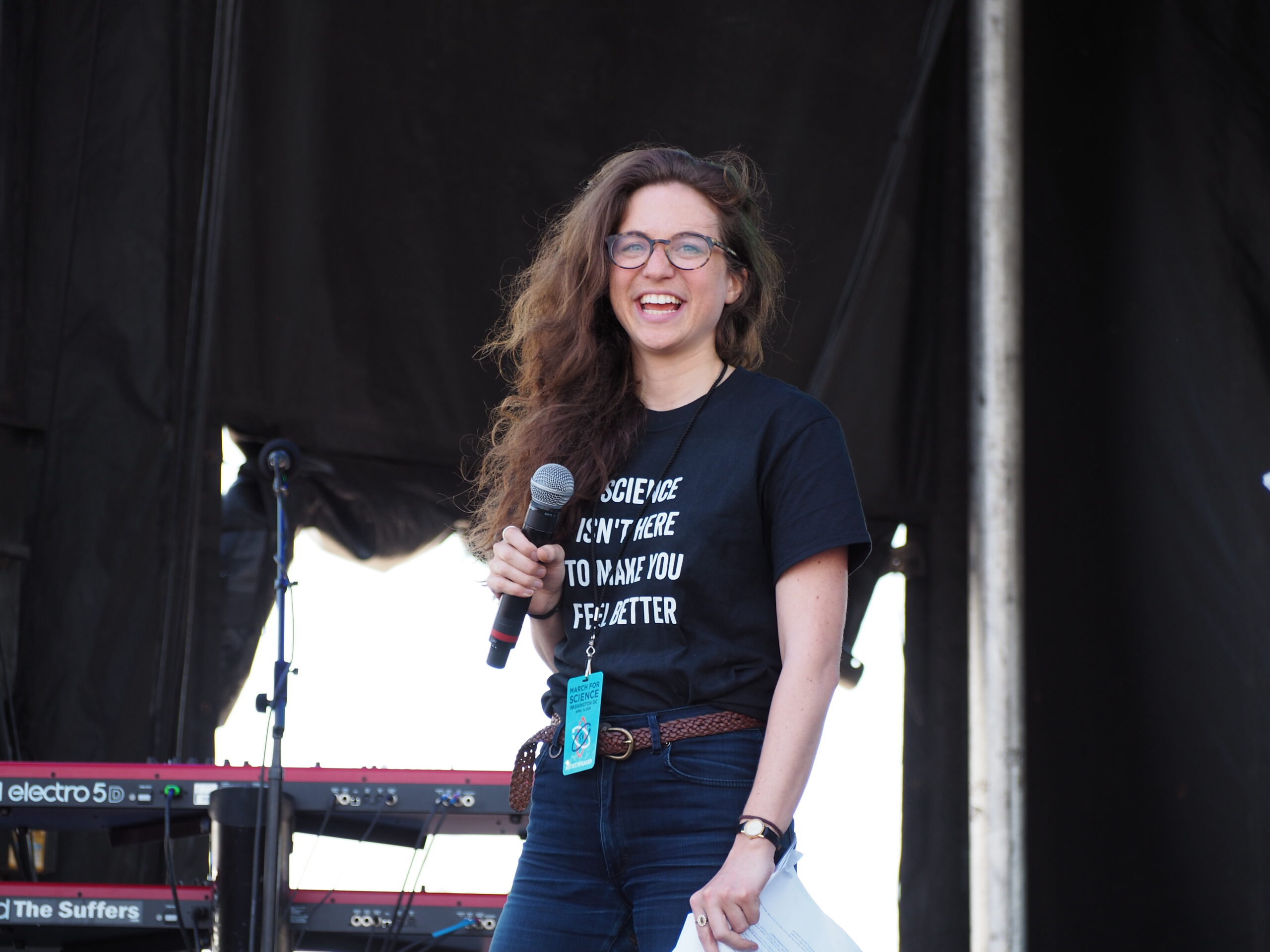 Photograph of Wendy Zukerman standing on a stage, wearing a t-shirt that says "Science isn't here to make you feel better."