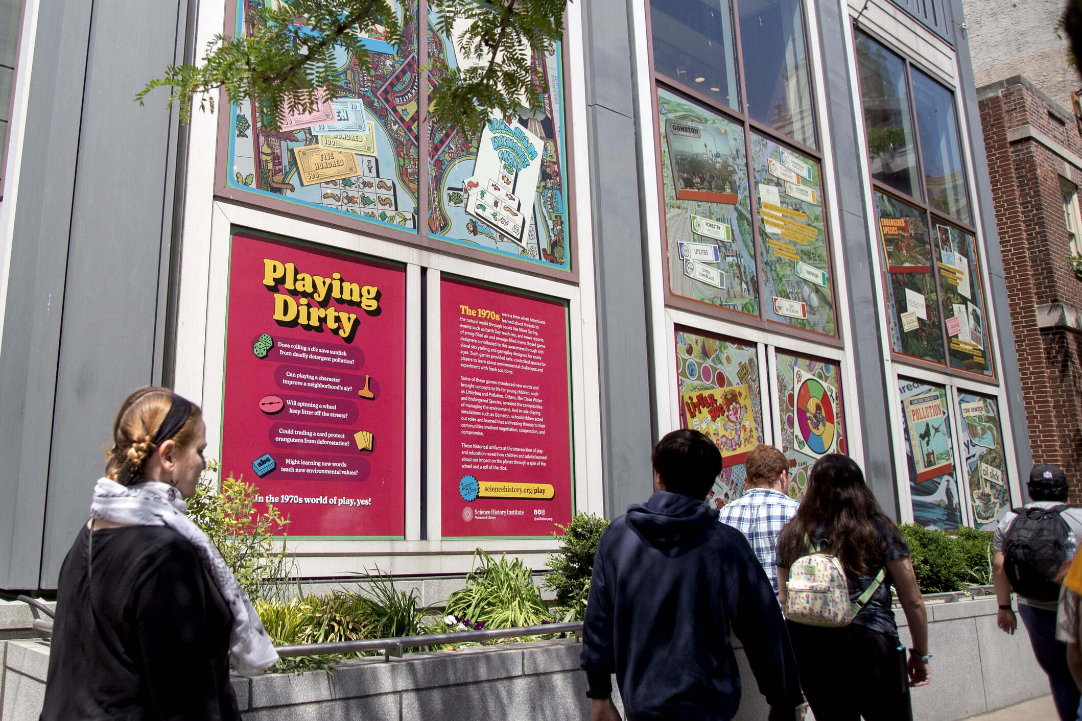 People walking near Playing Dirty outdoor exhibition