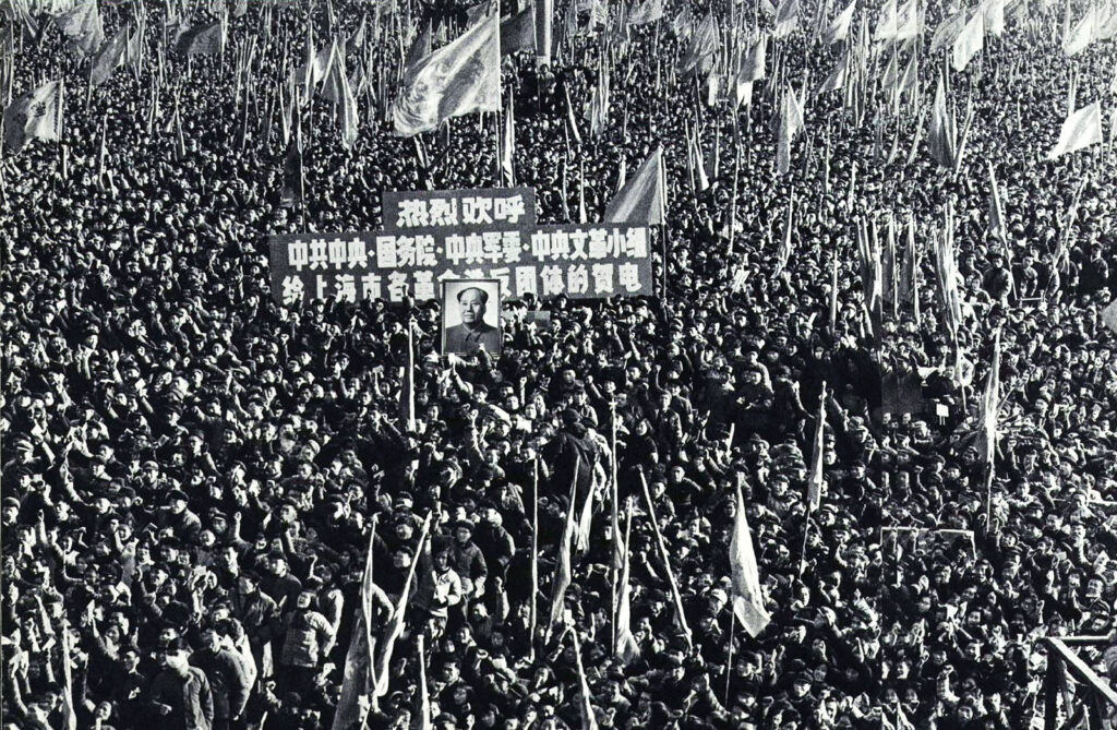 A large crowd of young people in military attire holding flags and a large banner