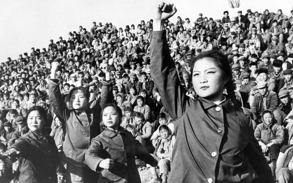 A woman stands with a raised fist in front of a crowd
