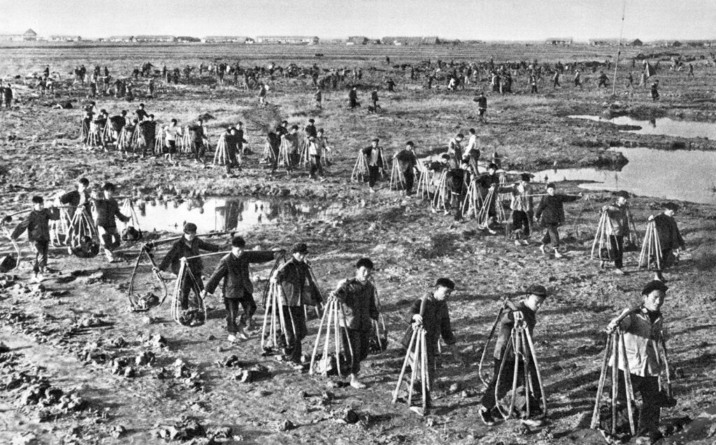 Black and white photo of people working a muddy field