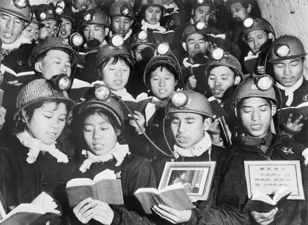 Coal miners stand in rows reading from books
