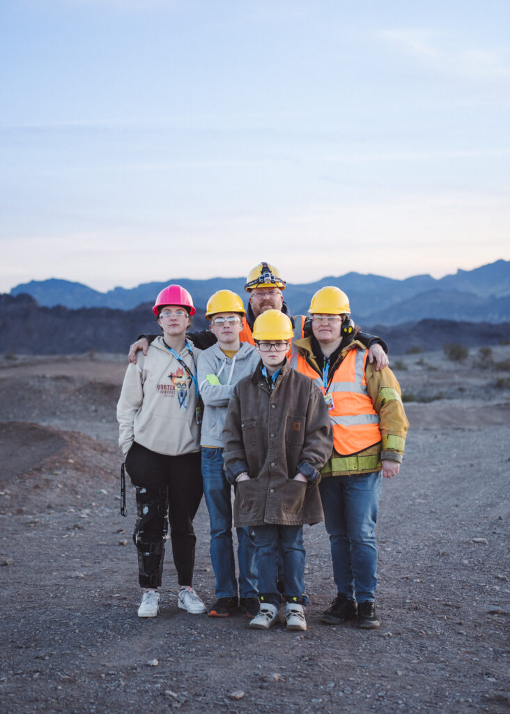 Portrait of a family standing in desert at dusk wearing hard hats 