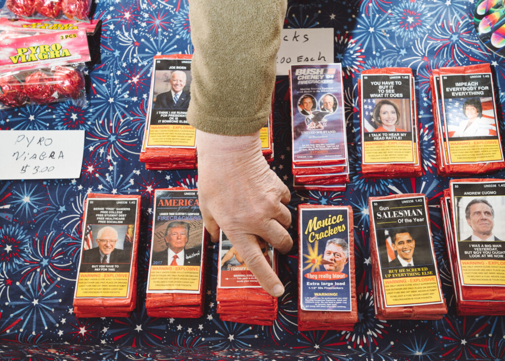 hand adjusting stacks of firework packs with political-themed wrappers
