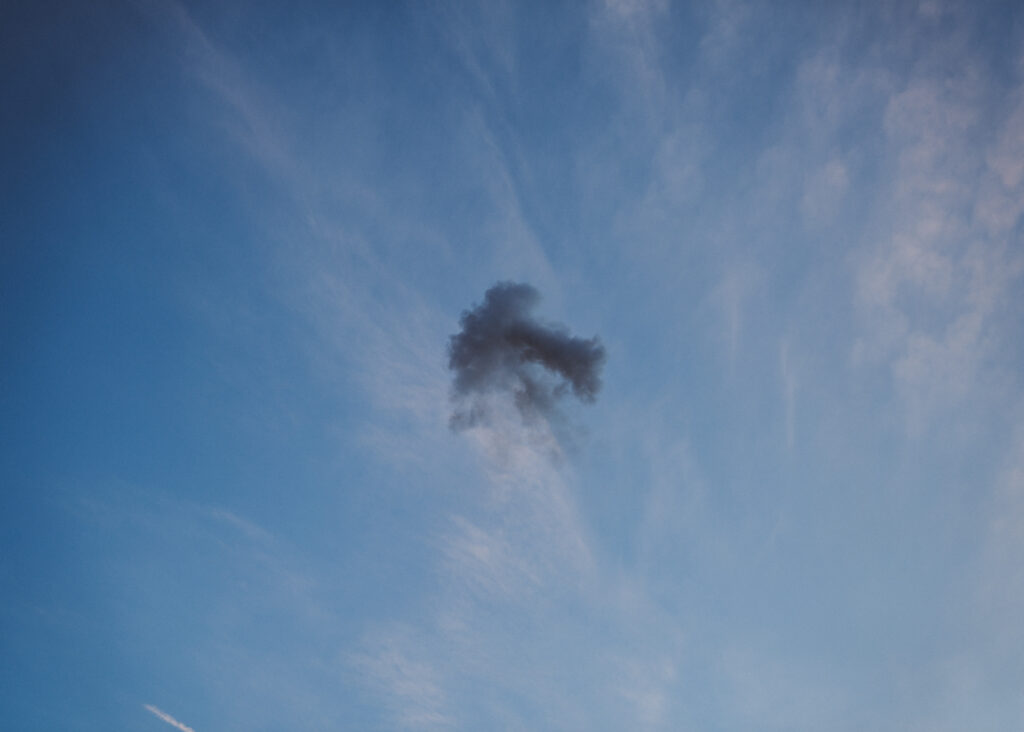 Small cloud of black smoke against blue sky