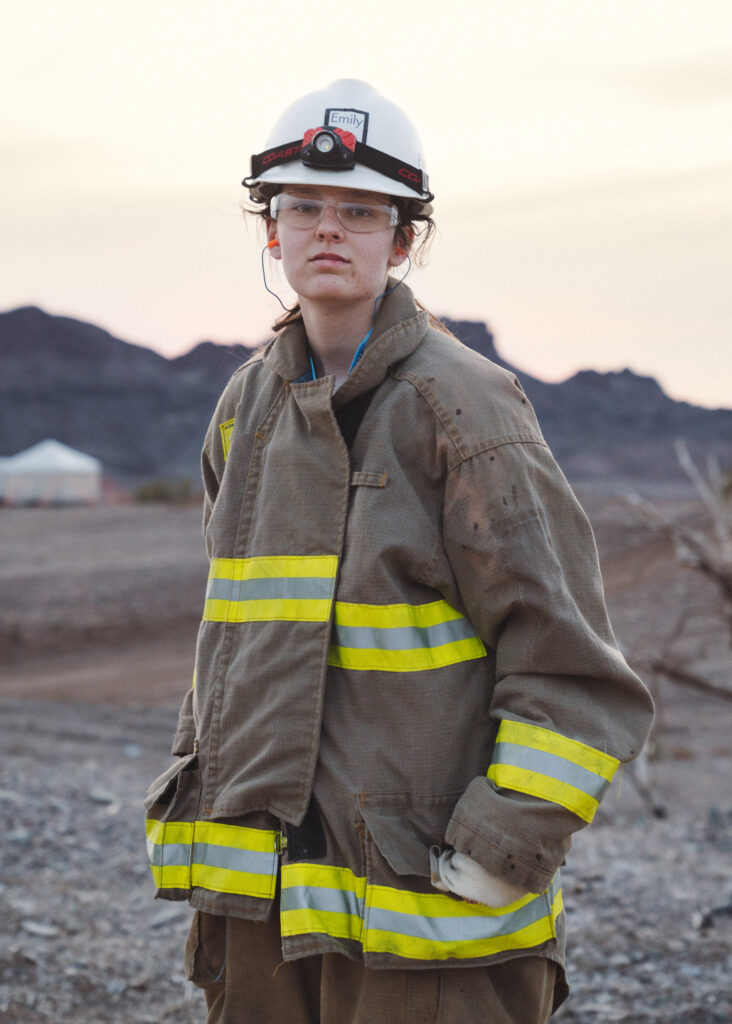 Portrait of teenage girl wearing hardhat and protective equipment slightly too big for her