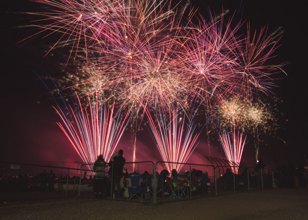 Large, fireworks display with silhouette of people in foreground