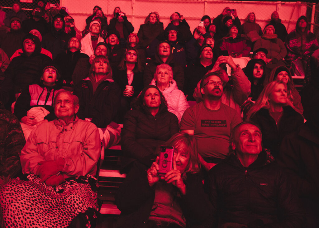 Photograph of red-tinged spectators seated in stands