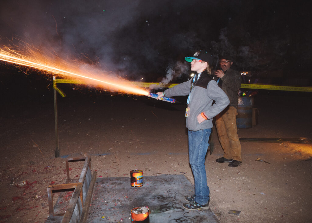 Teen calmly holding an flaring firework in his hand