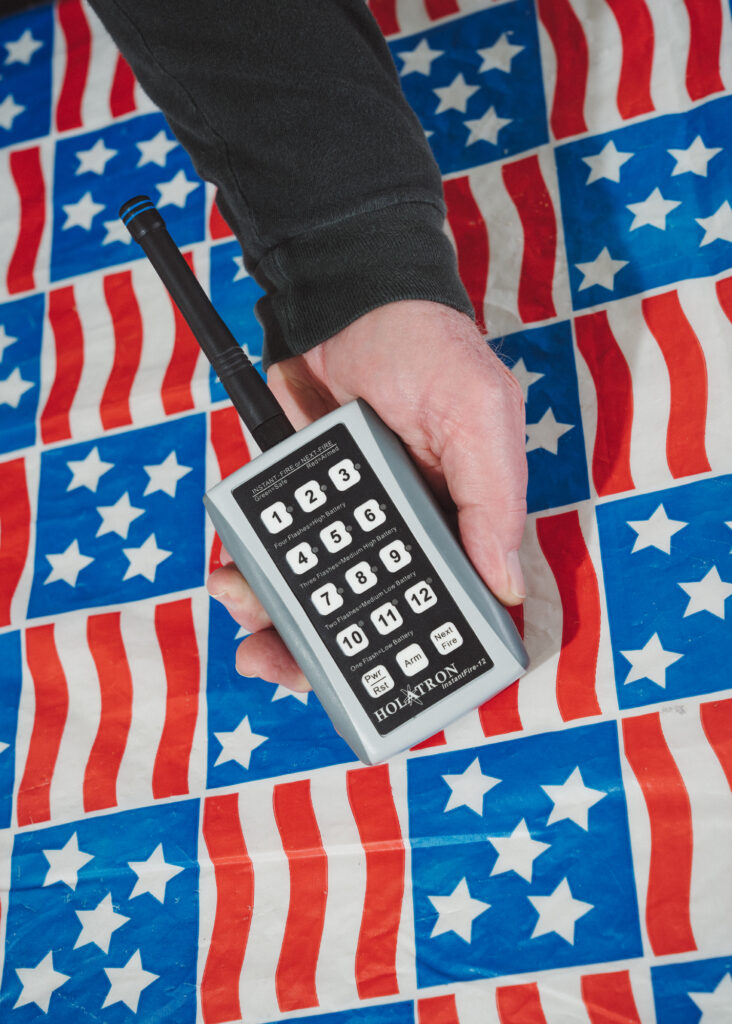 handing holding remote control over American flag patterned plastic tablecloth