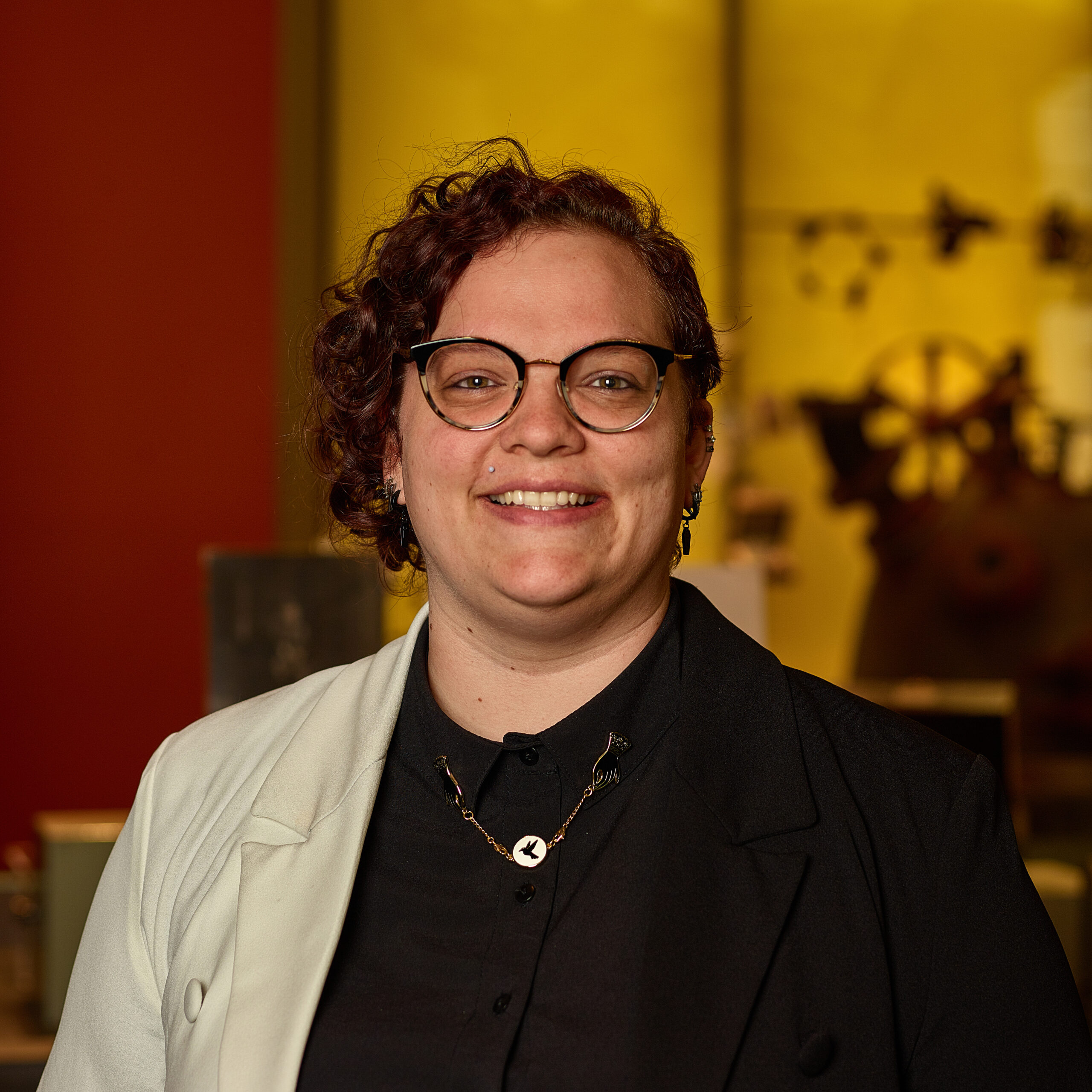 Erin in museum wearing glasses, black shirt, white blazer