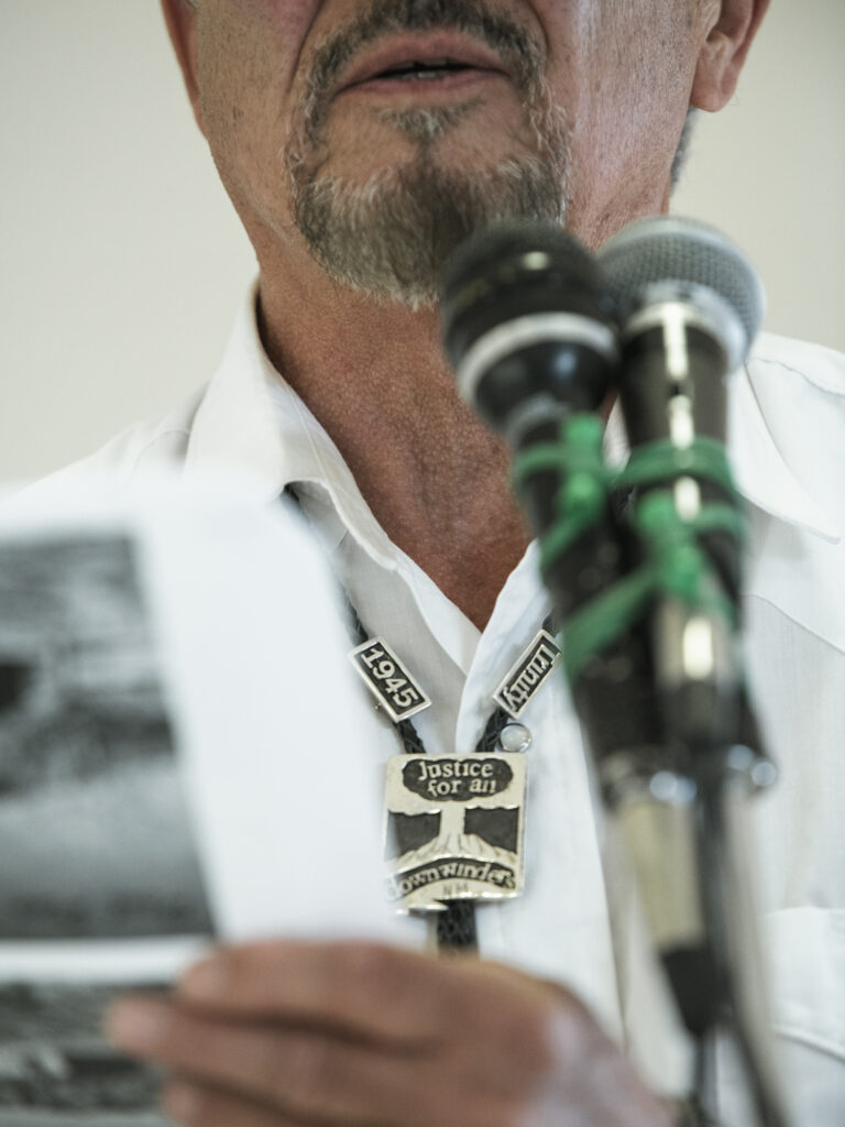 Close crop photo of a man with a Trinity downwinders themed bolo tie with image of mushroom cloud
