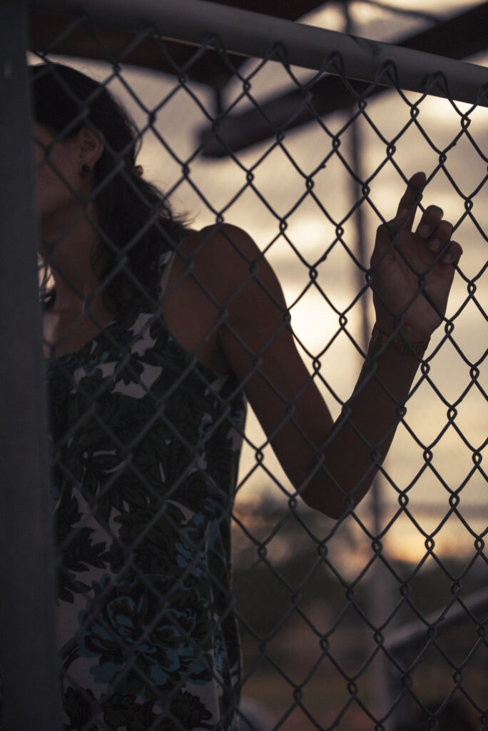 Media silueta de una mujer sosteniendo una cerca de tela metálica