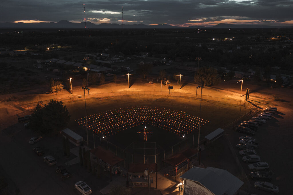 Drone photo of a baseball field illuminated by street lights and the the light lights of luminaries in the infield