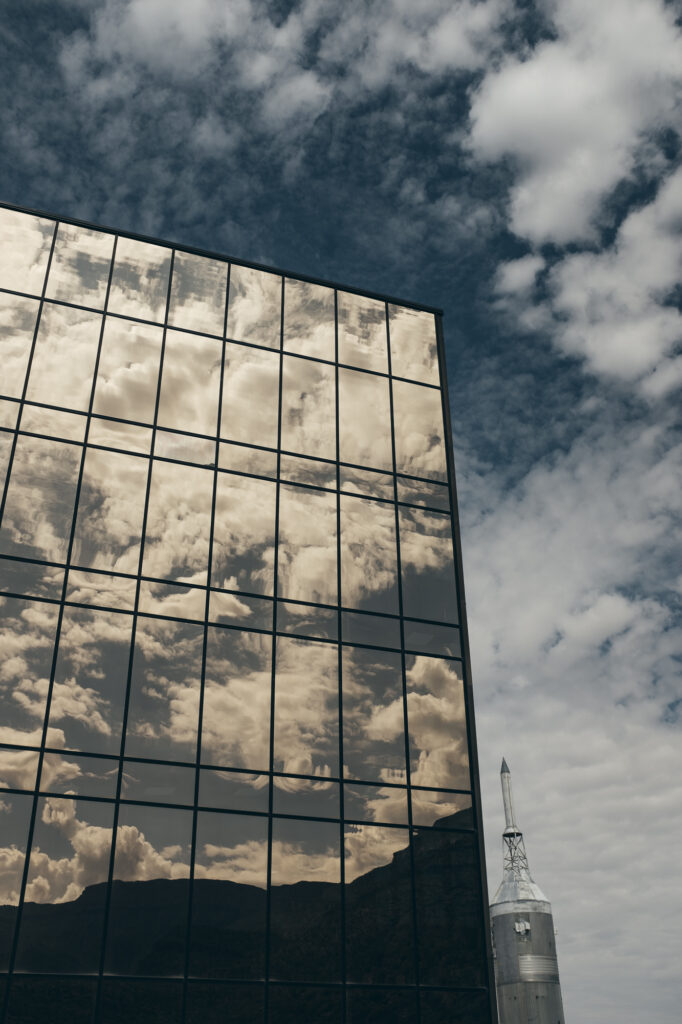 Photo of a glass building with clouds in its reflection