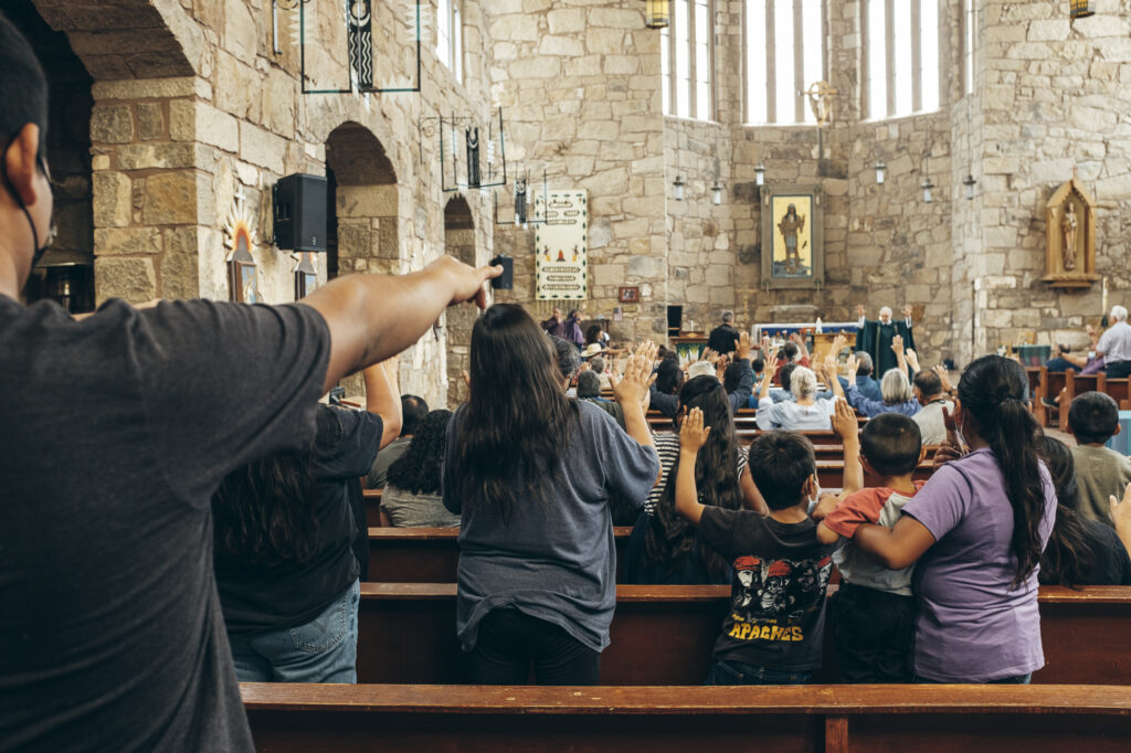 Foto de detrás de feligreses adorando en iglesia de piedra