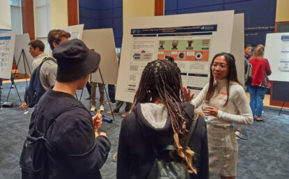 Scientist discussing her poster with visitors