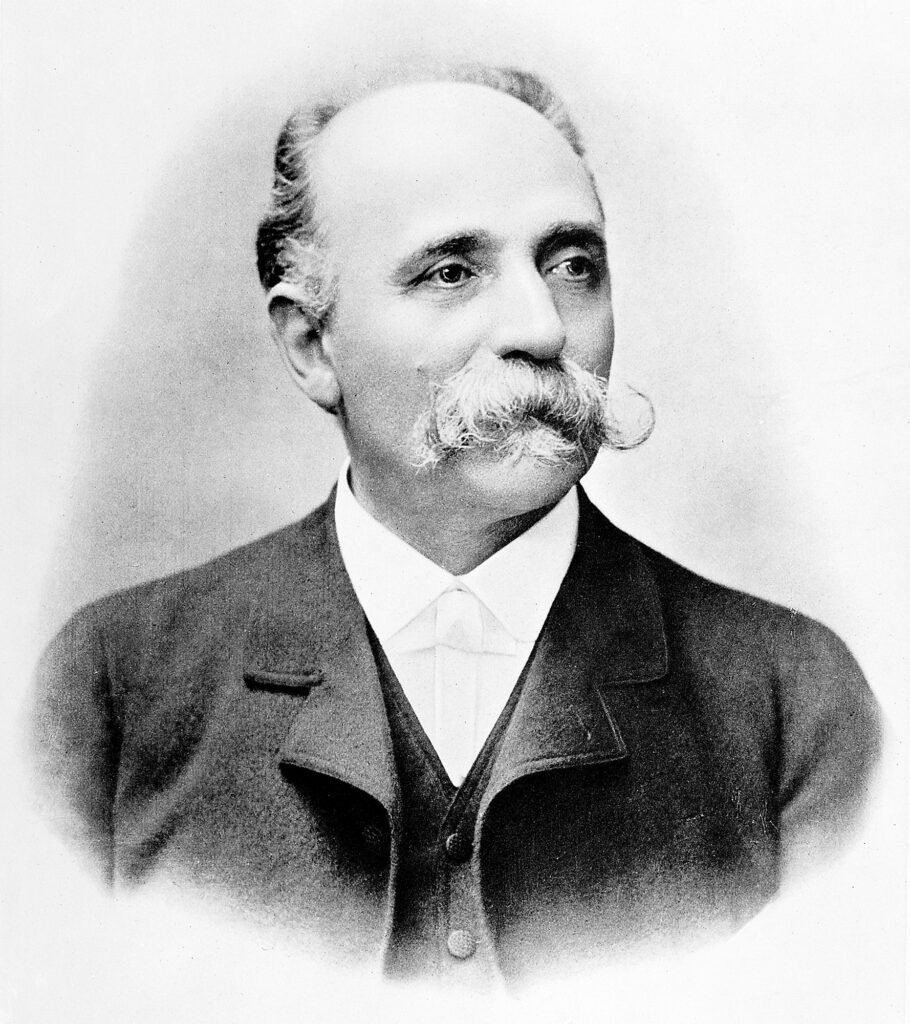 Black and white portrait of an older, balding man with a large mustache