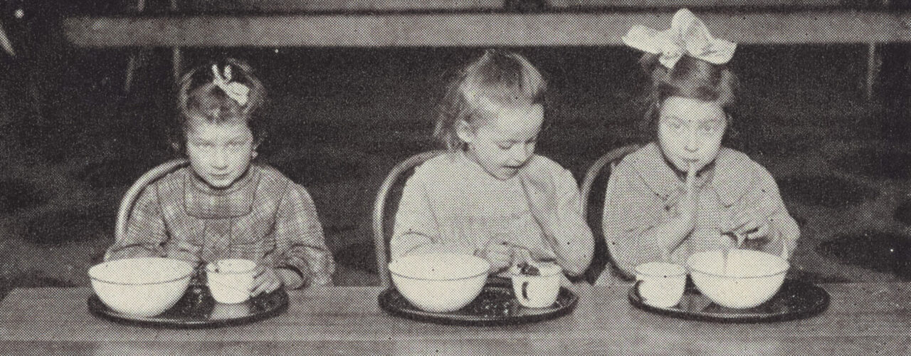 three children sitting at a table eating