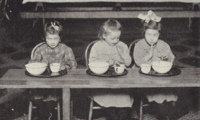 three children sitting at a table eating