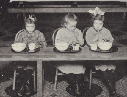 three children sitting at a table eating