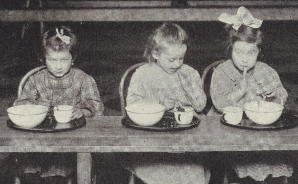 three children sitting at a table eating