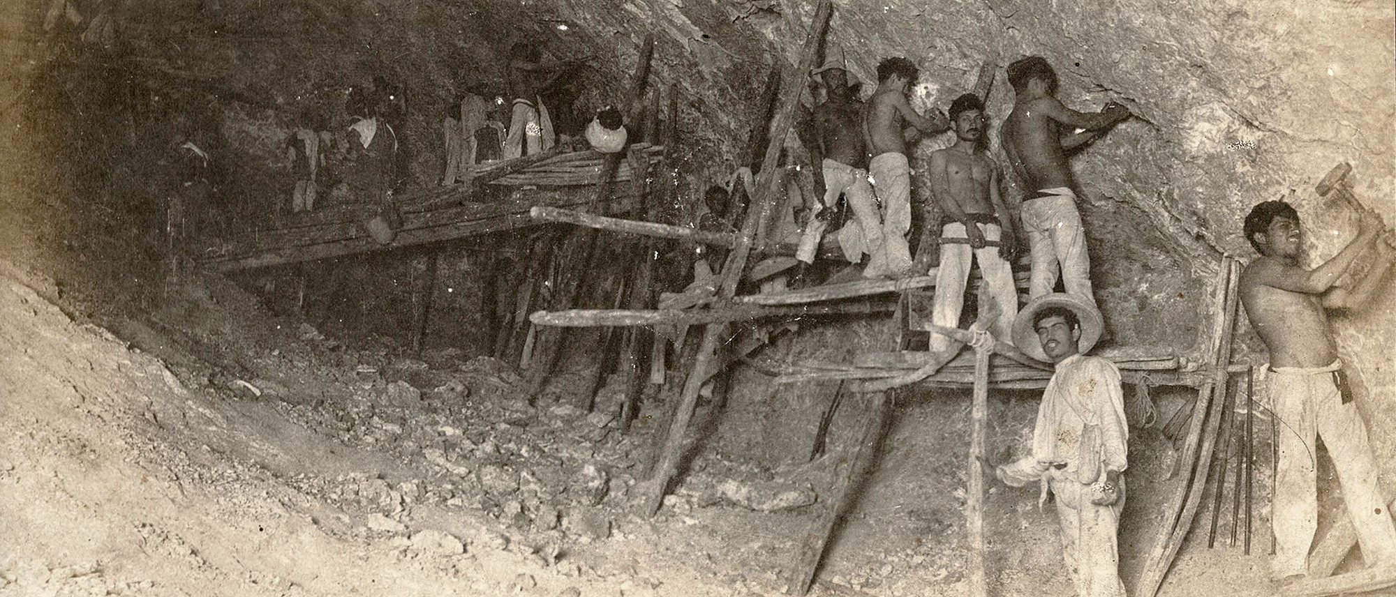 Black and white photo of men with hand tools working in a tunnel
