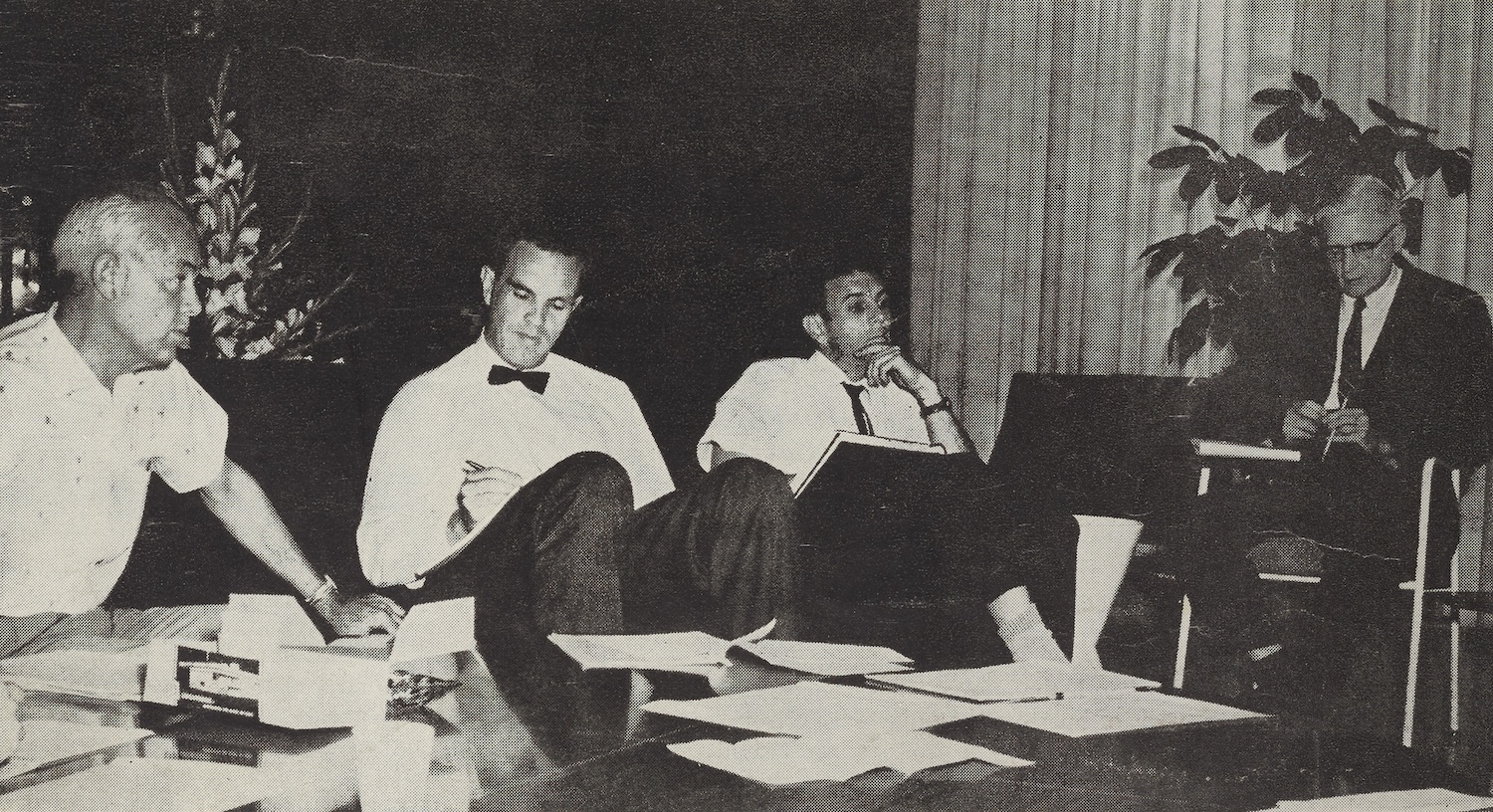black and white photo of men around a conference table