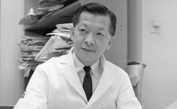 black and white photo of a seated man in a lab coat