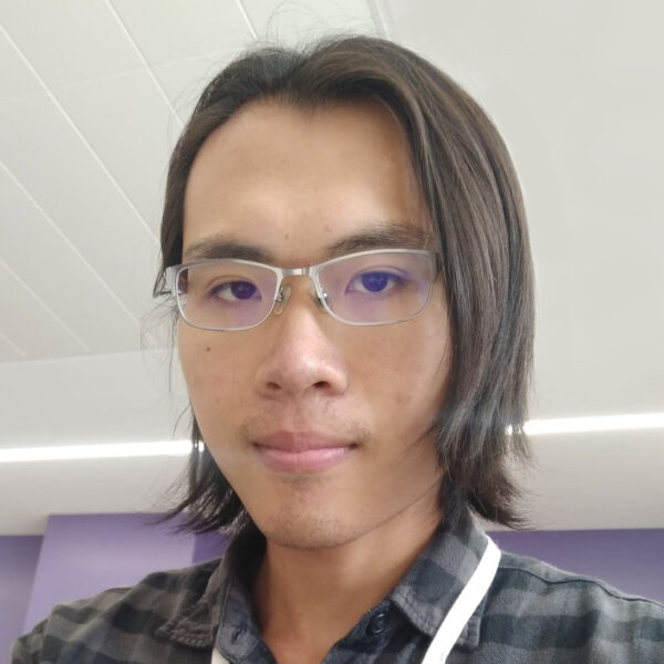 Leo Chu in gray and black checkered flannel, glasses, white lanyard