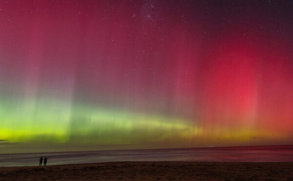 Color photograph of a vivid aurora in the sky over a beach