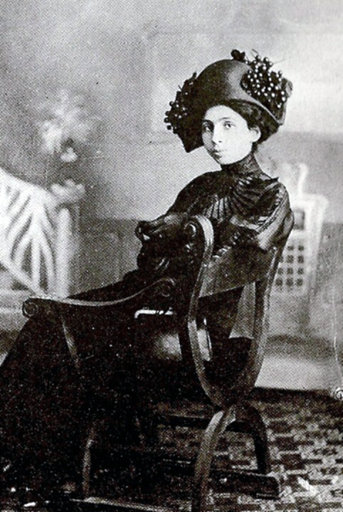 Black and white photo of a seated young women in dark, elegant attire