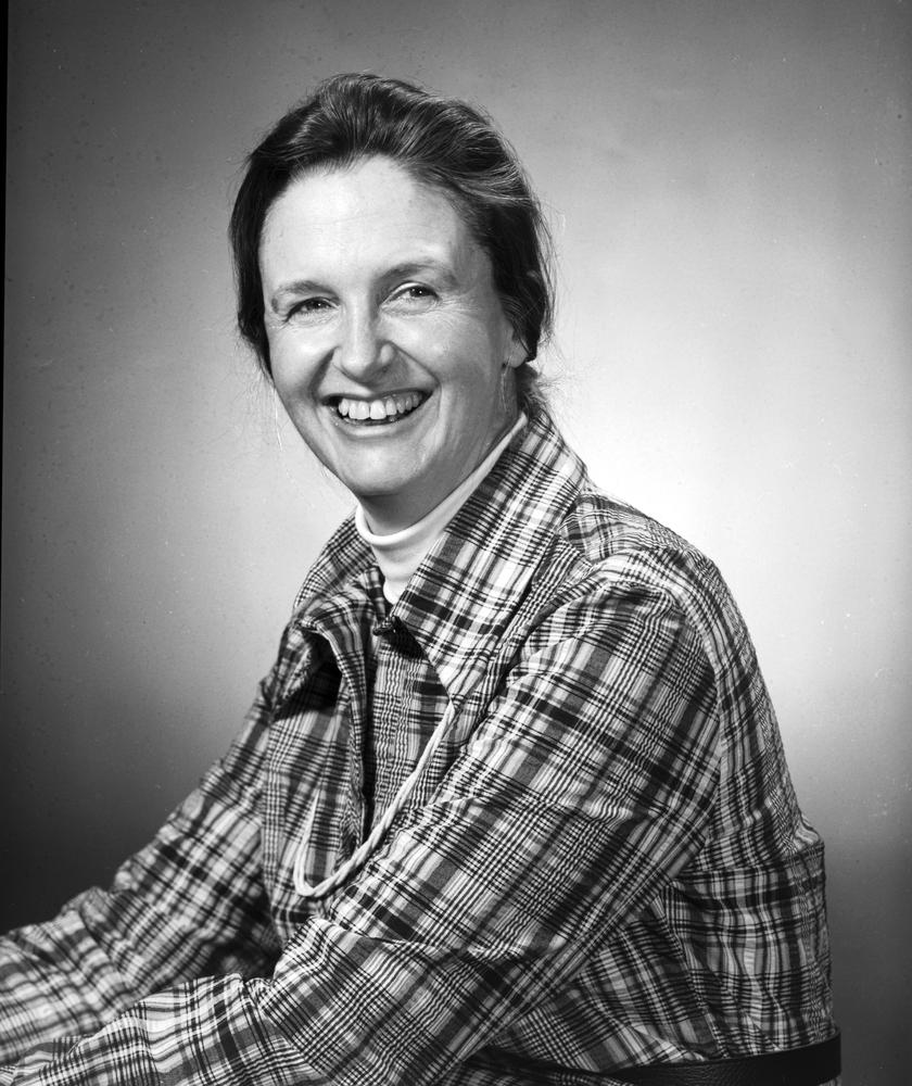 Black and white portait of a smiling women in a plaid shirt