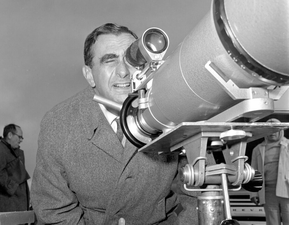 Black and white photo of a man looking through a large viewfinder