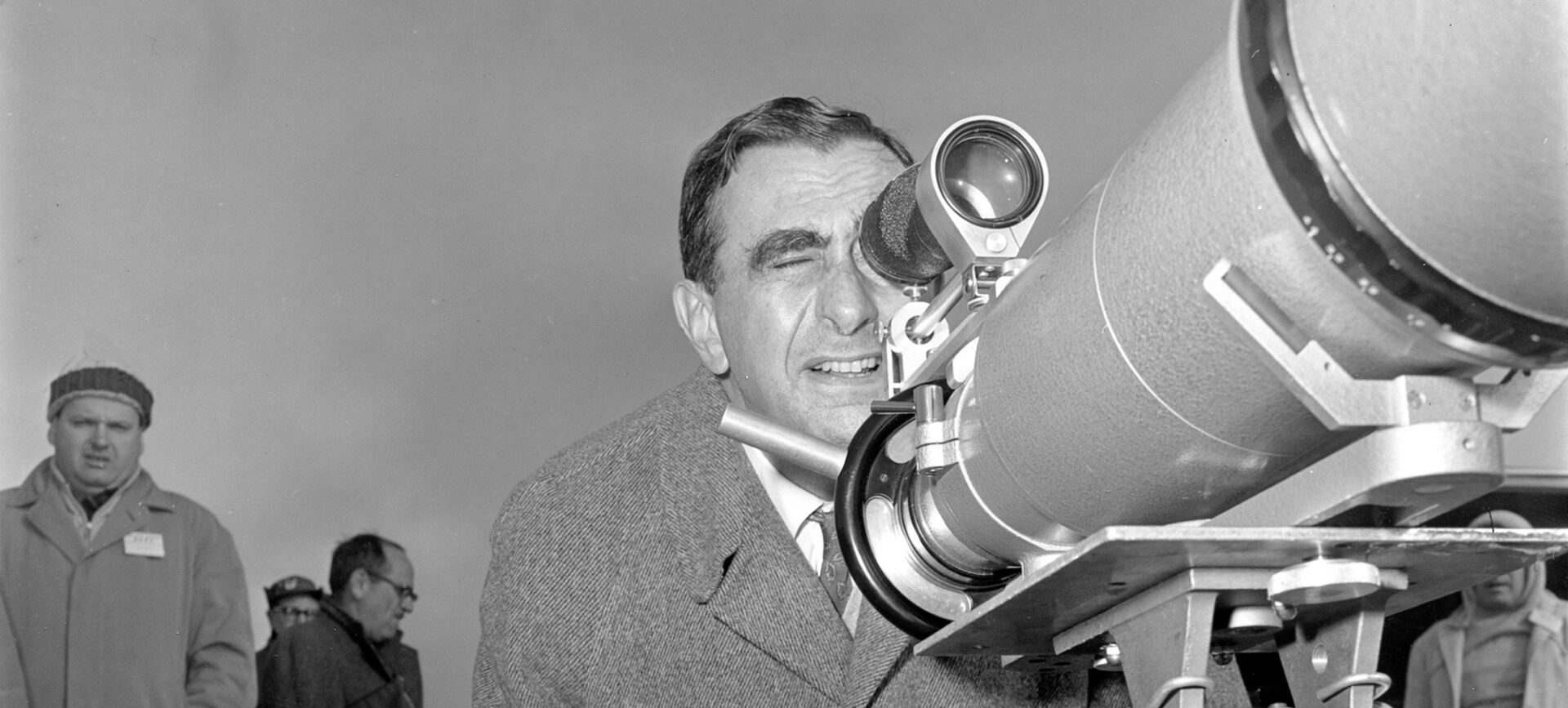 Black and white photo of a man looking through a large viewfinder