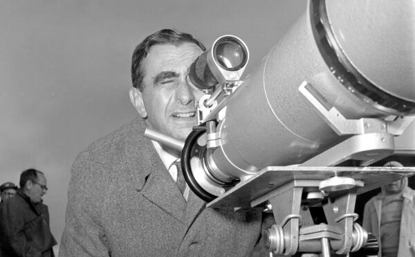 Black and white photo of a man looking through a large viewfinder