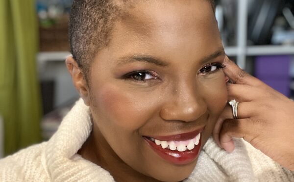 Alexis in cowl neck off-white sweater, smiling, cheek resting on hand