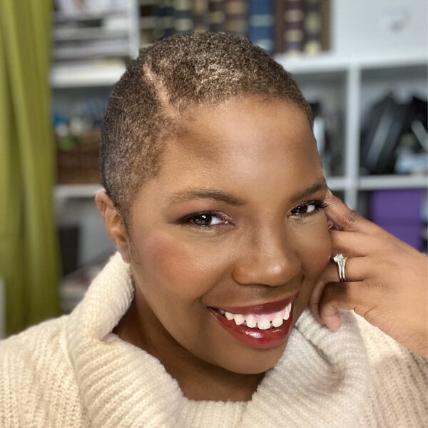 Alexis in cowl neck off-white sweater, smiling, cheek resting on hand