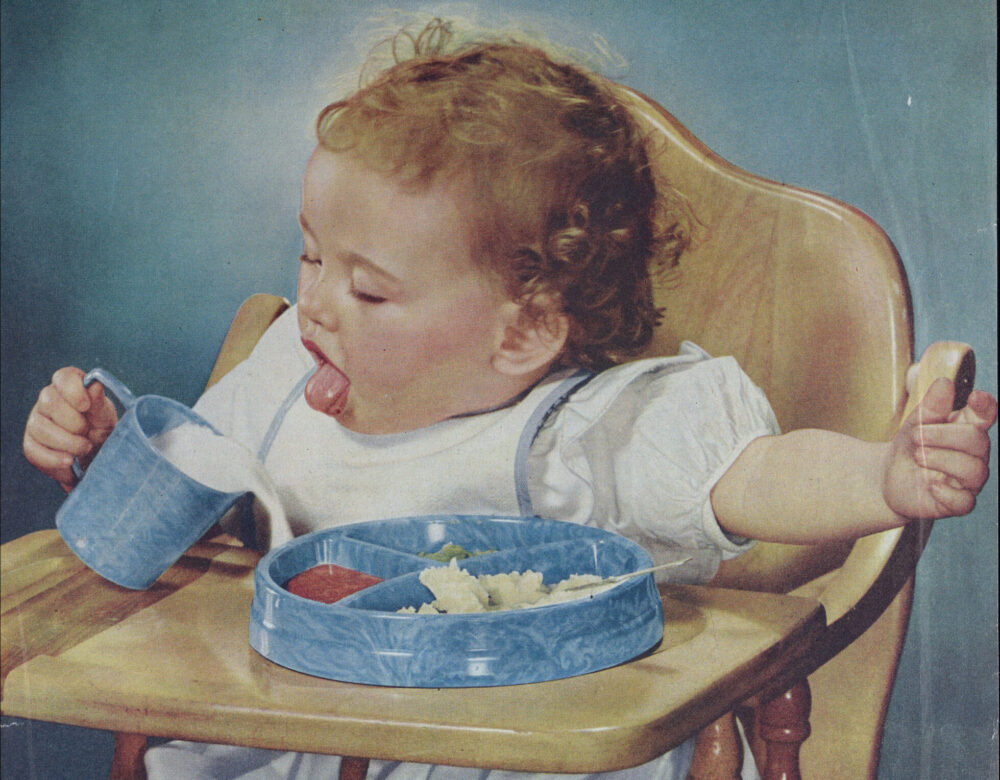 magazine ad featuring a baby in high chair pouring milk over a tray