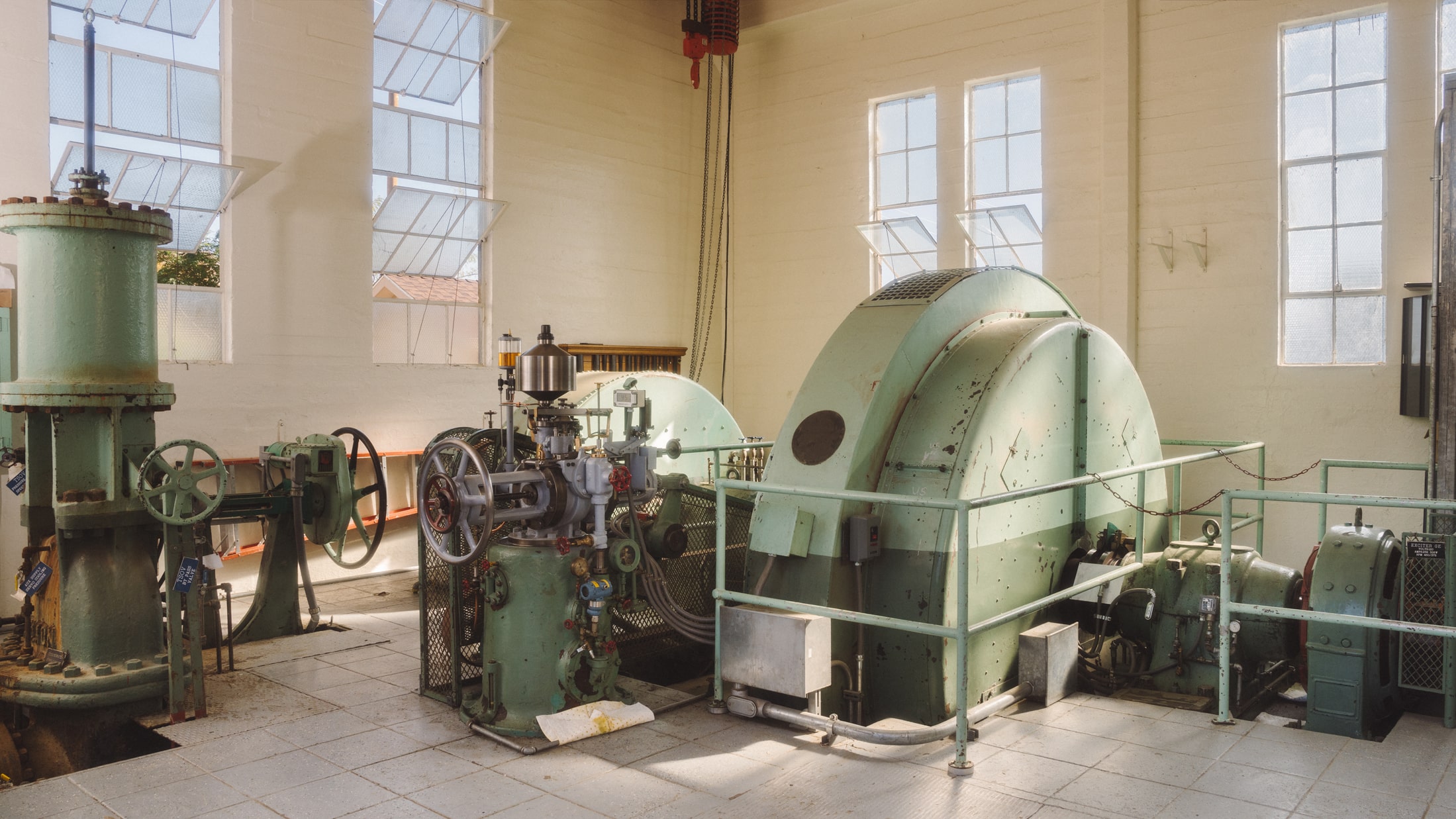 Powerplant interior with high windows, white tile floor, and equipment painted green