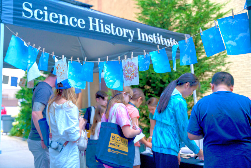 patrons outdoors around a tent working on botanical dye crafts