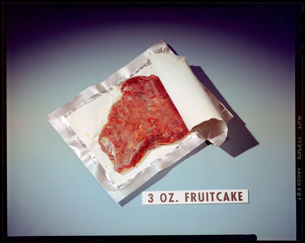 Staged color photo of a piece of dehydrated fruit cake in an open laminate pouch