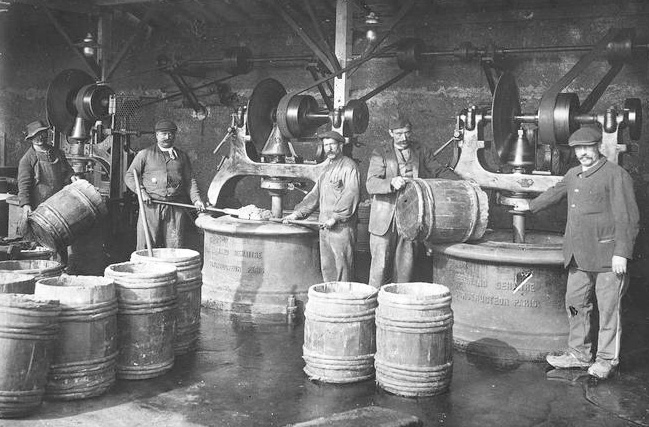 Old photo of men loading barrels with powder in an industrial setting