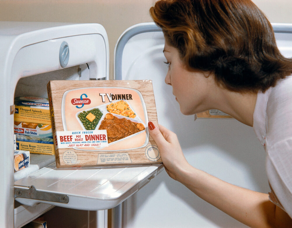 A woman examines a TV dinner box she has taken from the freeze