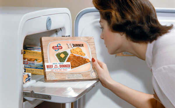 A woman examines a TV dinner box she has taken from the freeze