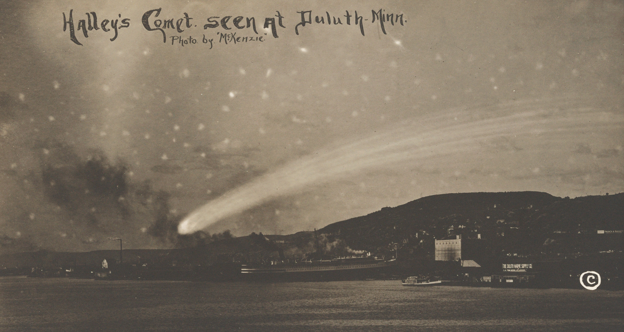 Old photo postcard showing a small city at night above a river with a large comet overhead